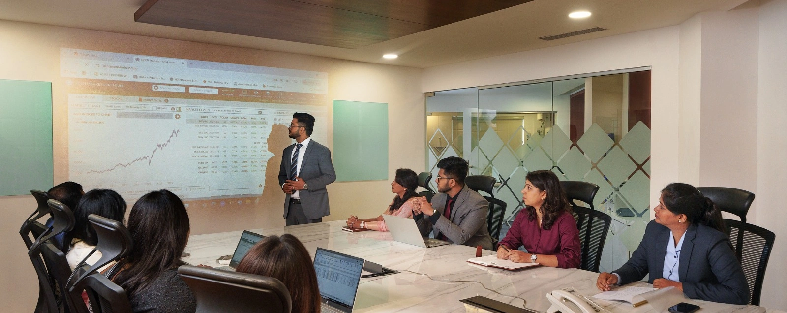 Financial professionals in a business meeting reviewing projected charts and data