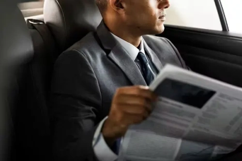 Business professional reading newspaper in car